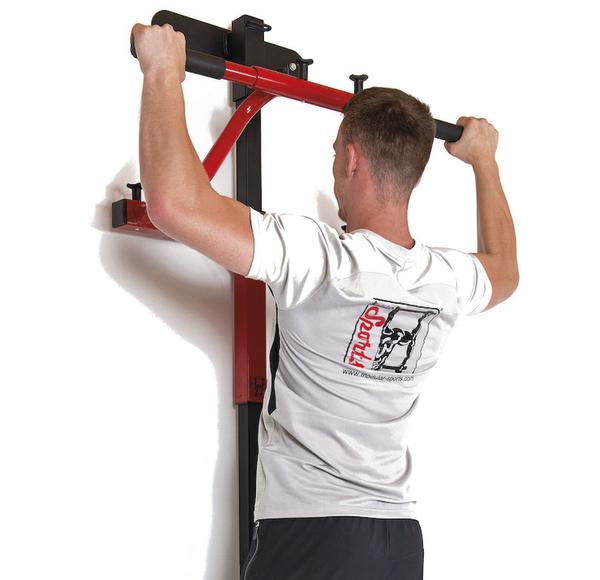 Mann macht Klimmzüge an roter Wand-Klimmzugstange mit weißer Wand im Hintergrund.