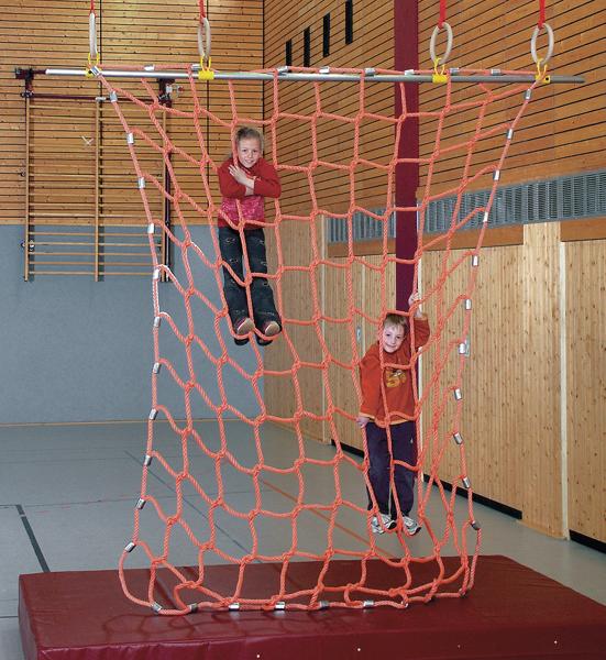 Kindermädchen klettern an einem orangen Kletternetz in einer Turnhalle.