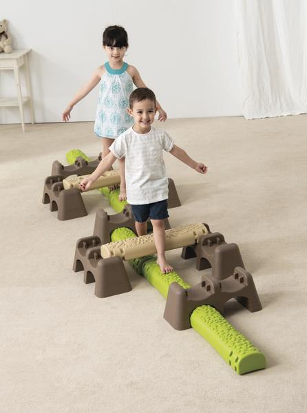 Kinder balancieren auf einem Indoor-Spielplatz mit Kletter- und Balanciergeräten aus Kunststoff.