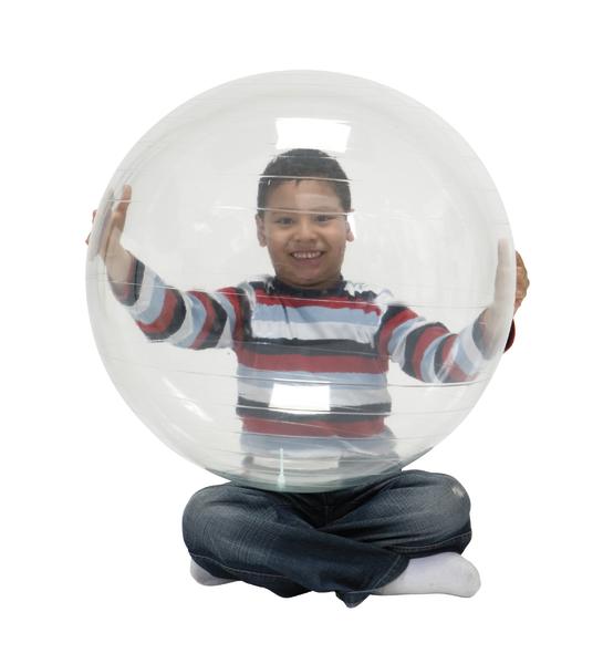 Junge sitzt im Schneidersitz und hält großen transparenten Gymnastikball vor sich.