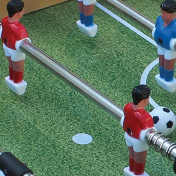 Detailaufnahme des Spielfelds eines Tischkickers mit Figuren in Rot und Blau sowie Ball.
