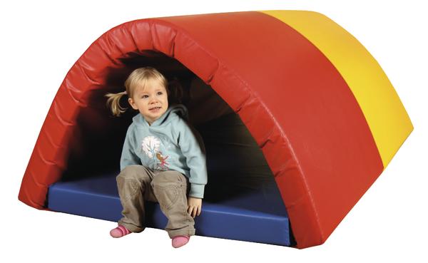 Kind sitzt in buntem Spieltunnel aus Schaumstoff, rot, gelb, blau, Indoor-Spielzeug.