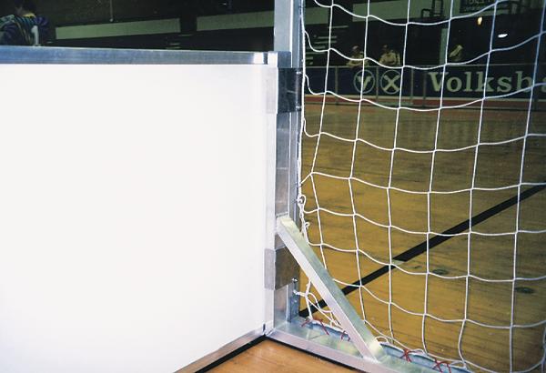 Innenaufnahme eines Handballtors mit Netz und Hallenboden im Hintergrund.