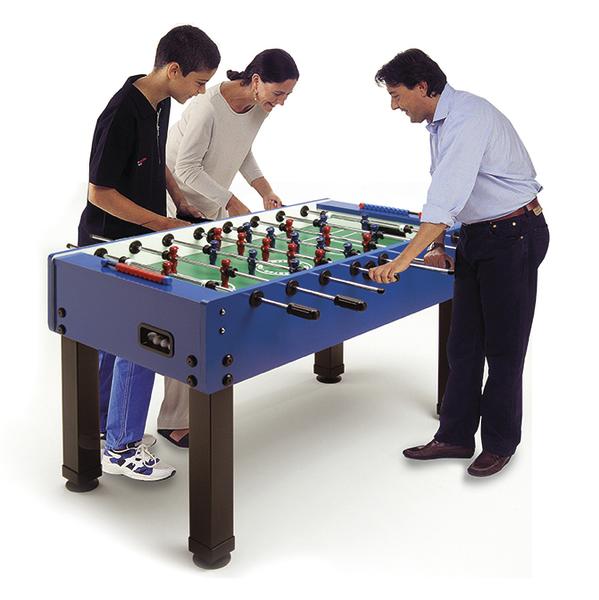 Drei Personen spielen an einem blauen Tischkicker und beugen sich konzentriert über das Spielfeld.