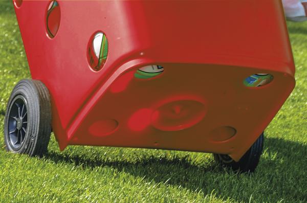 Rotes Kunststoffspielzeug mit Rädern auf grünem Rasen, geeignet für Kinder im Freien.