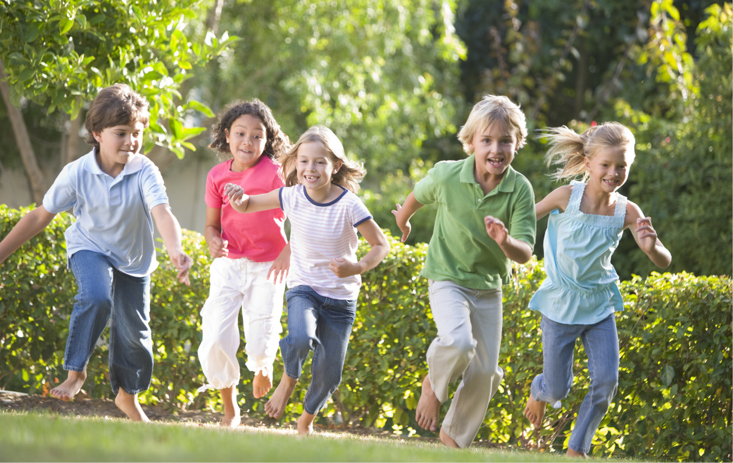 Fünf Kinder rennen über eine Wiese