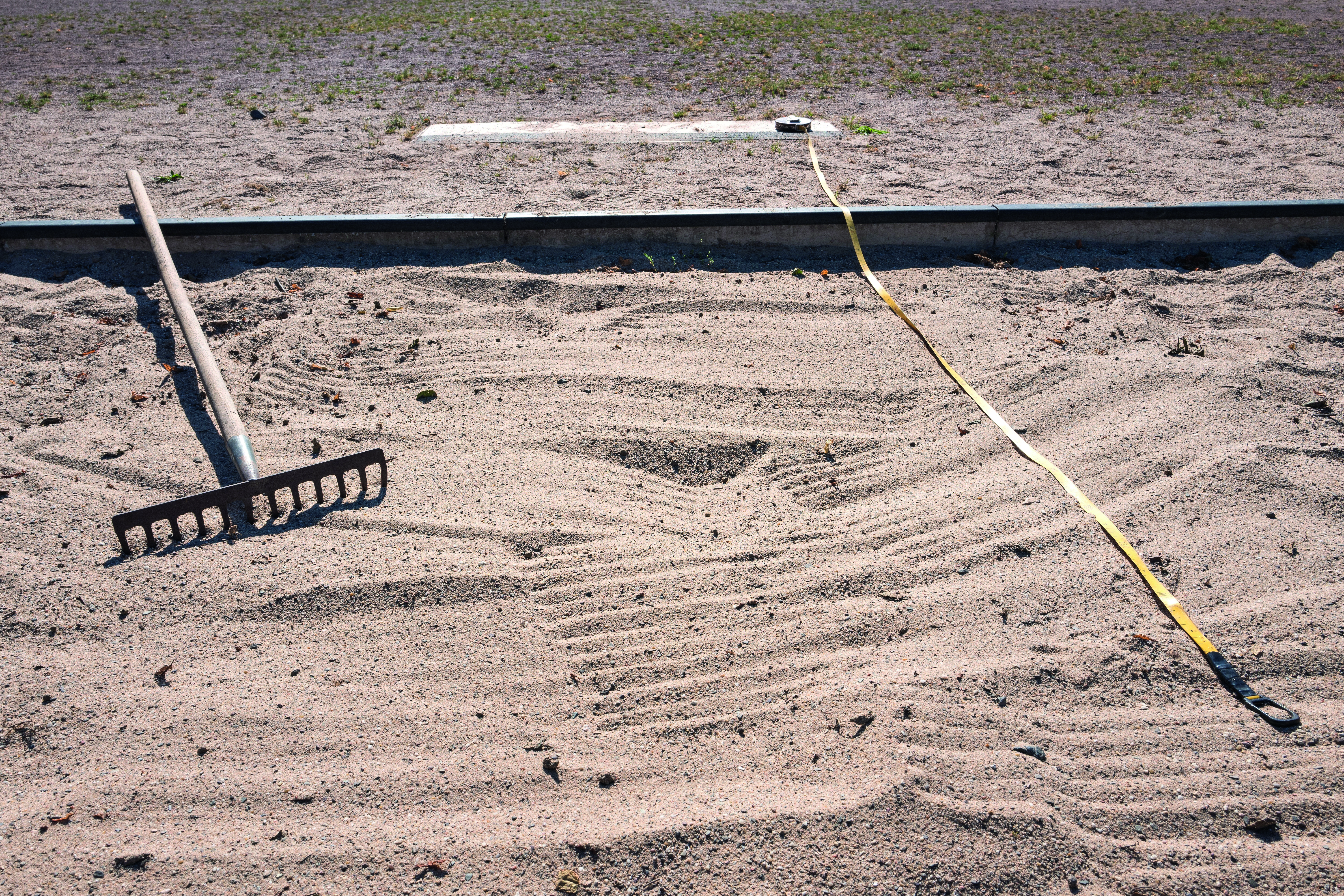 Sandgrube beim Weitsprung mit Rechen und Massband