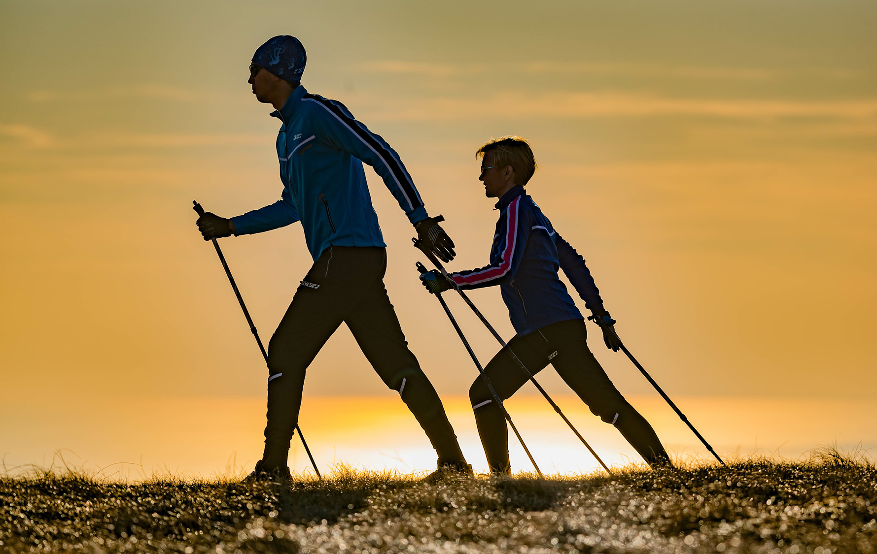 zwei Menschen führen Nordic Walking aus