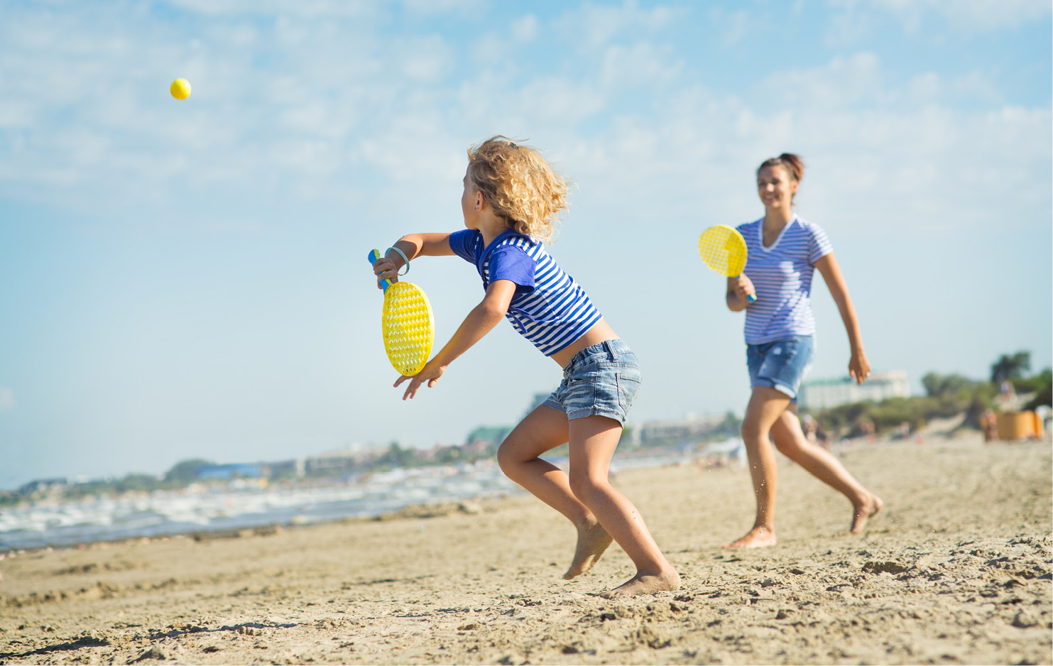 Kind und Frau spielen Beachball