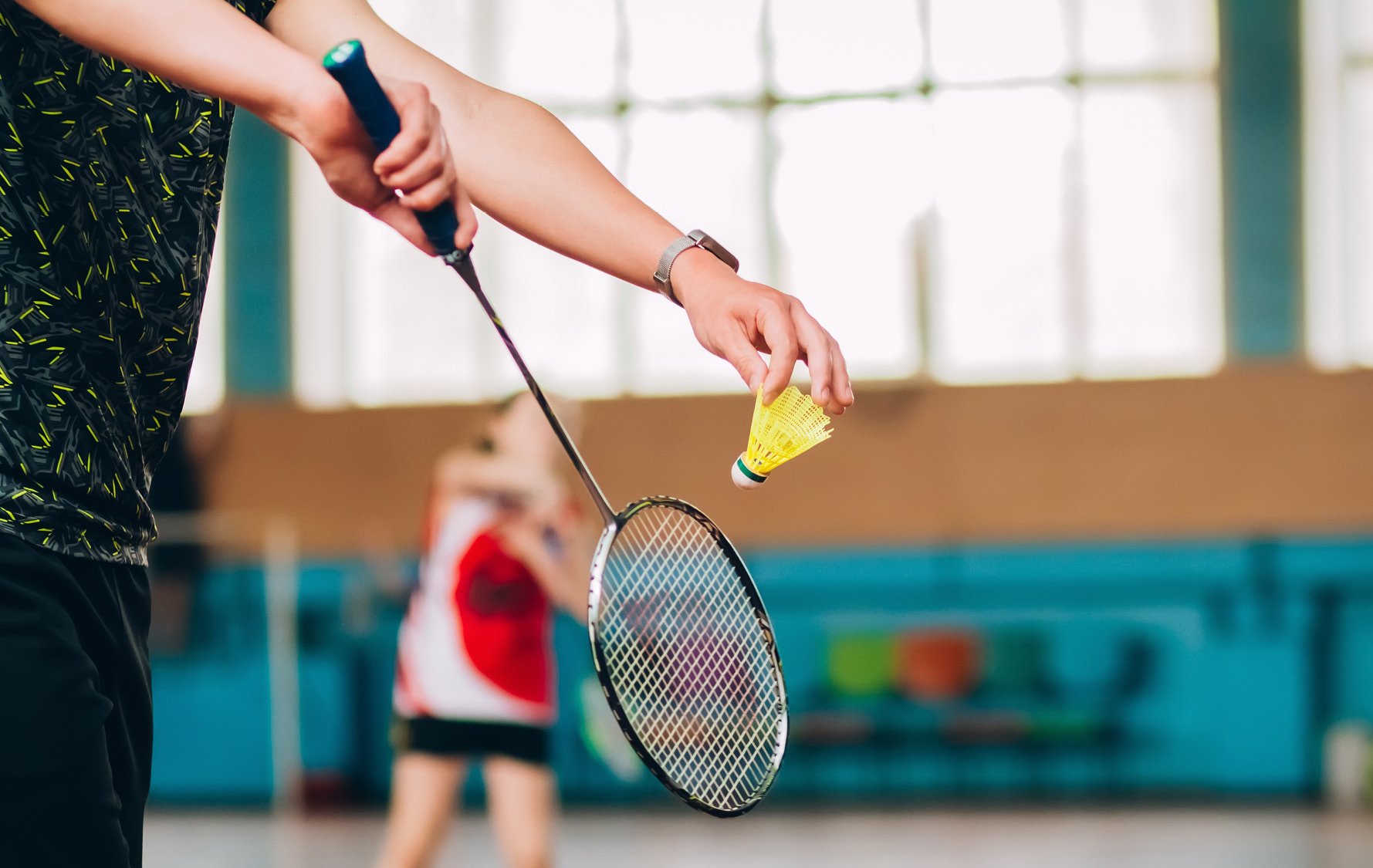 Bild zeigt Hand inkl. Badmintonball vor Abschlag durch den Schläger