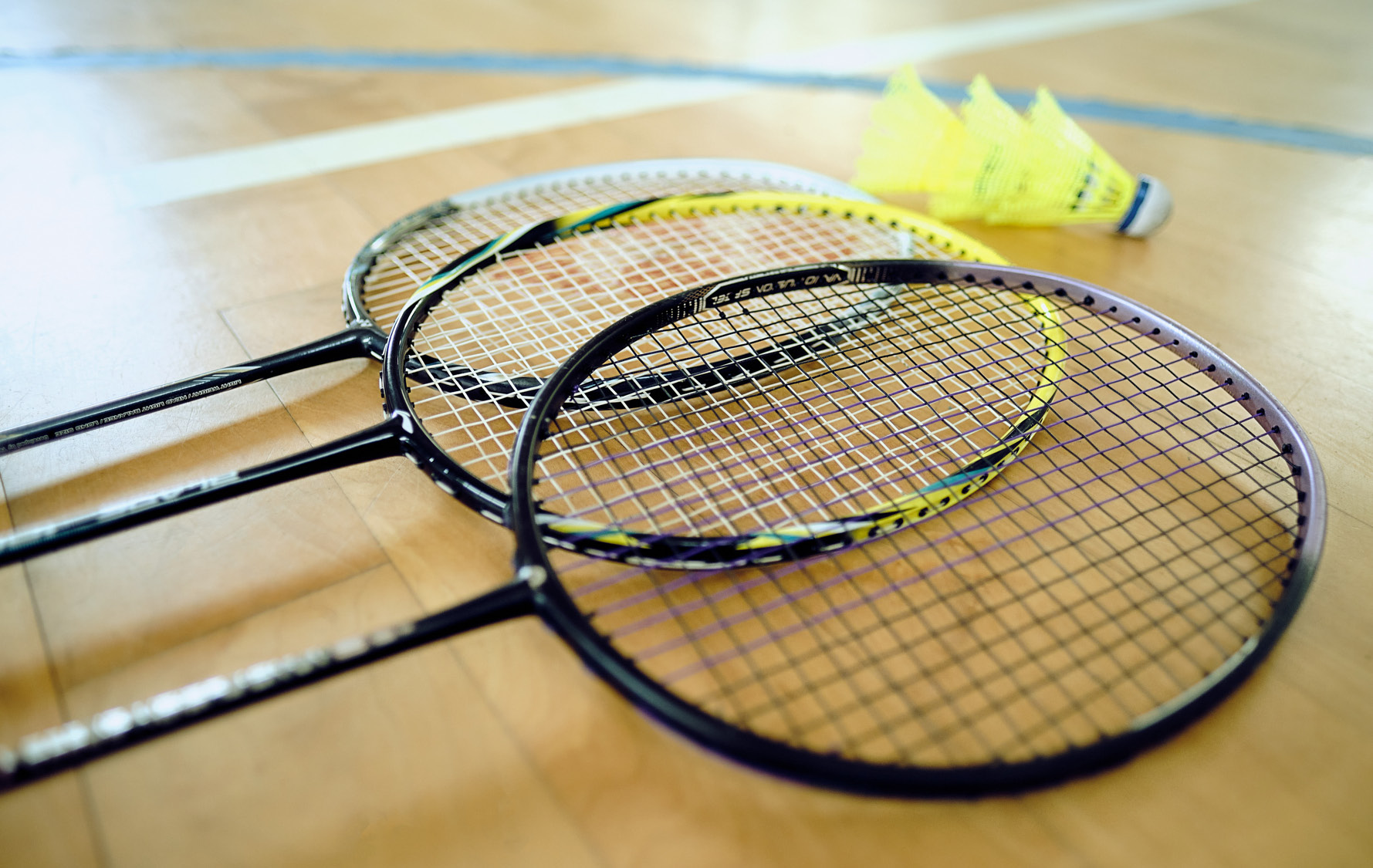 Drei Badmintonschläger liegend auf dem Sporthallenboden